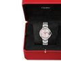 A Cartier Ballon Bleu de Cartier wristwatch with Roman numeral markers and a round face is showcased in an open red Cartier box lined with black velvet.