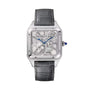 The Cartier Santos-Dumont Skeleton with Micro-Rotor features a square face, blue hands, visible mechanical movement, and a grey leather strap—exemplifying minimalism and elegance against a white background.
