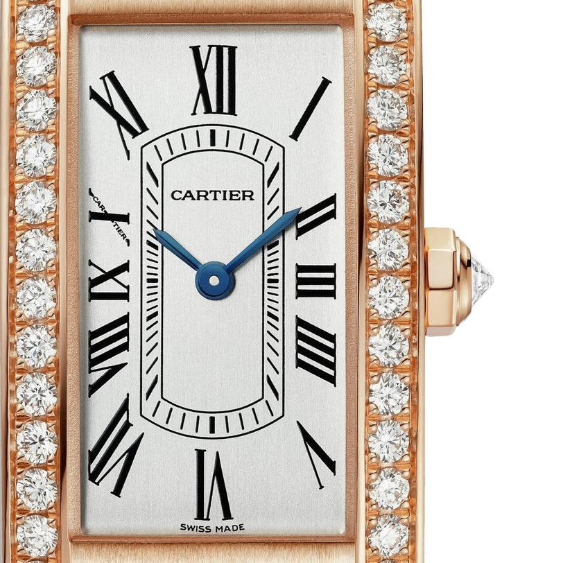 Close-up of the Cartier Tank Américaine watch featuring a rectangular face, rose gold case, diamond-encrusted bezel, Roman numeral markers, and blue hands.