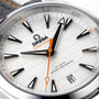 Close-up of an OMEGA Seamaster Aqua Terra 150M watch face with black hour markers, an orange seconds hand, and date set to 11. The dial features Co-Axial Master Chronometer, showcasing its precise calibre 8900 movement.