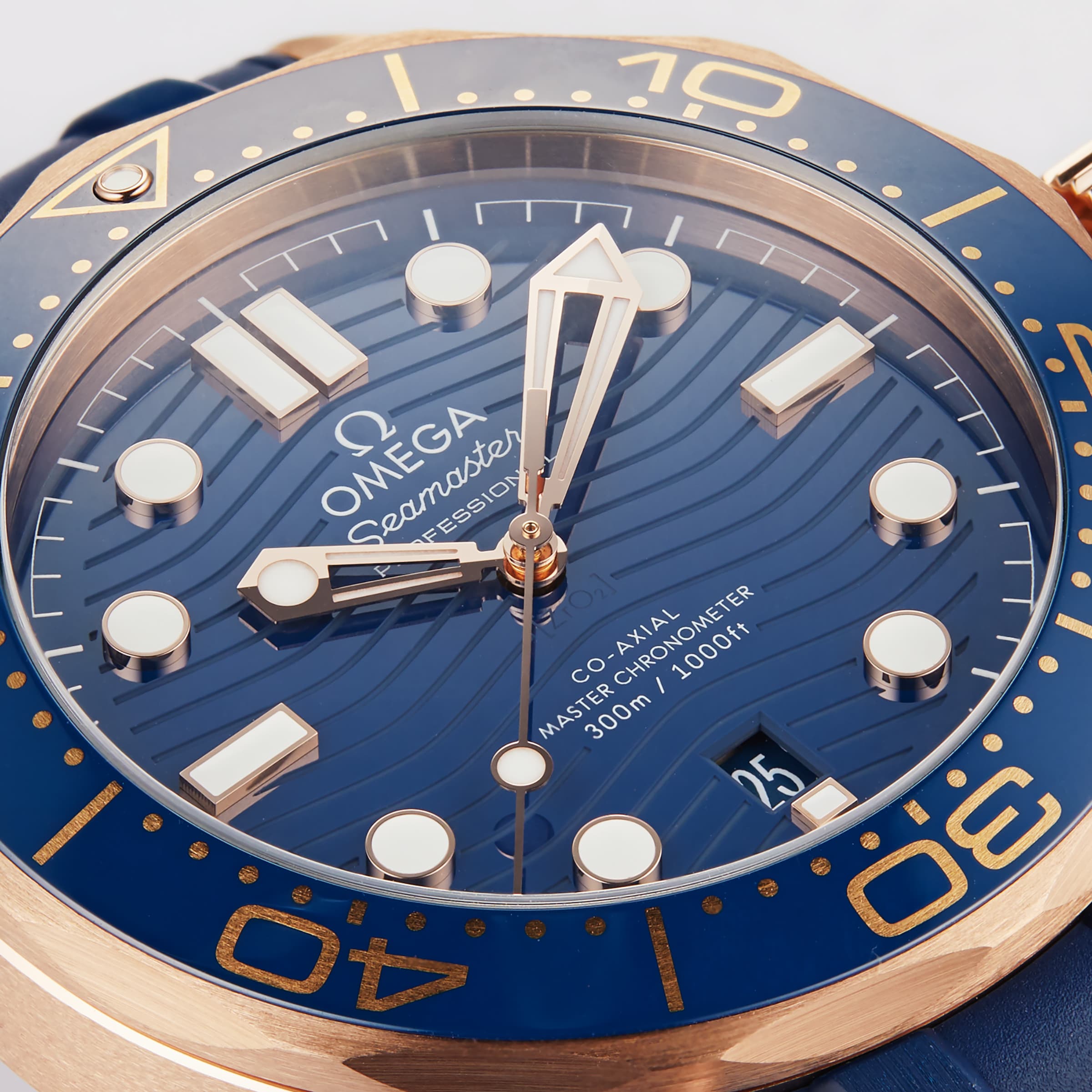 Close-up of an OMEGA Seamaster Diver 300M watch, featuring a blue wave-patterned dial, gold accents, and a blue bezel with numerals—an iconic dive timepiece.