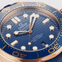 Close-up of an OMEGA Seamaster Diver 300M watch, featuring a blue wave-patterned dial, gold accents, and a blue bezel with numerals—an iconic dive timepiece.