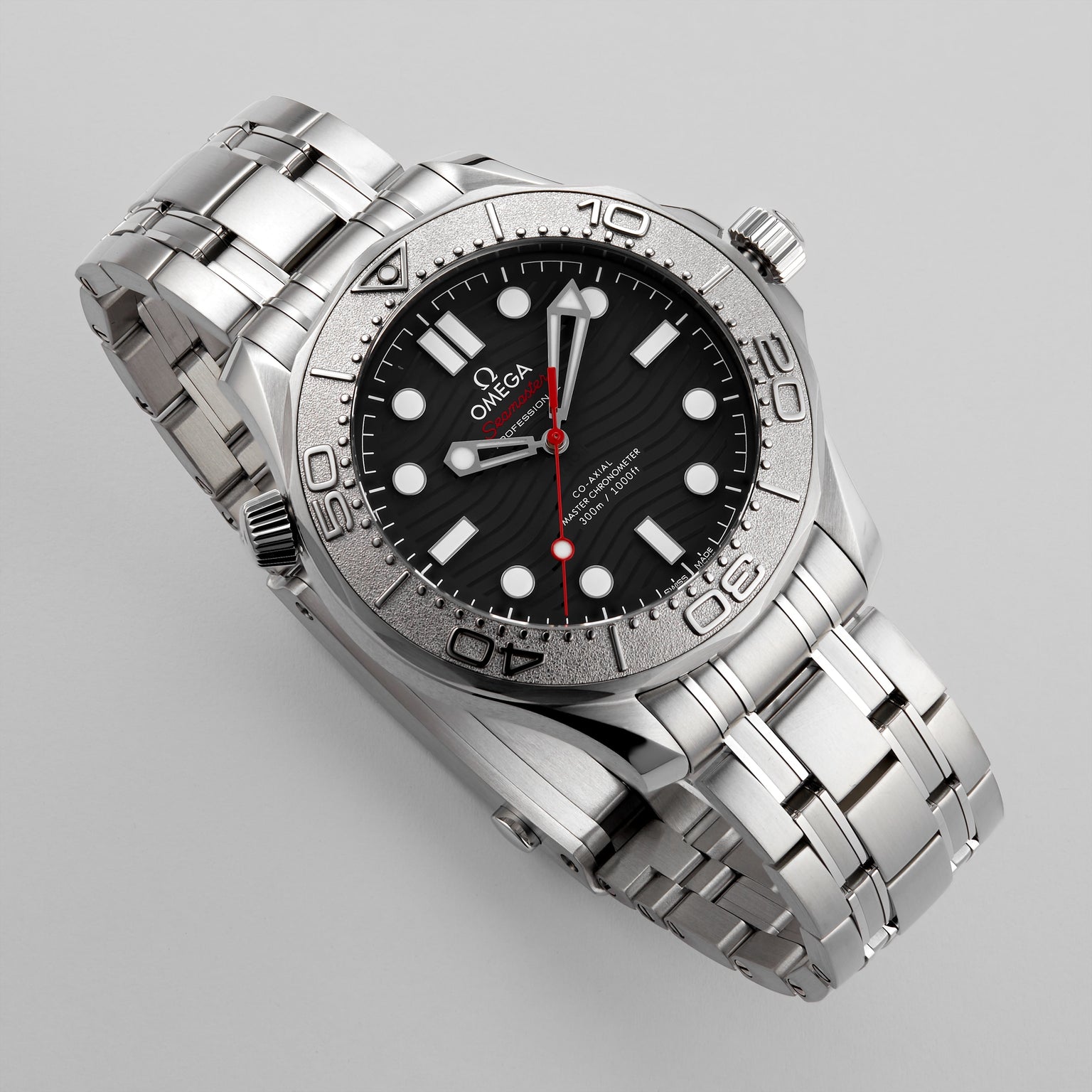An OMEGA Seamaster Diver 300M Nekton Edition in stainless steel with a black, wave-pattern ceramic dial, white markers, red second hand, and metal bracelet shown on a light gray background.