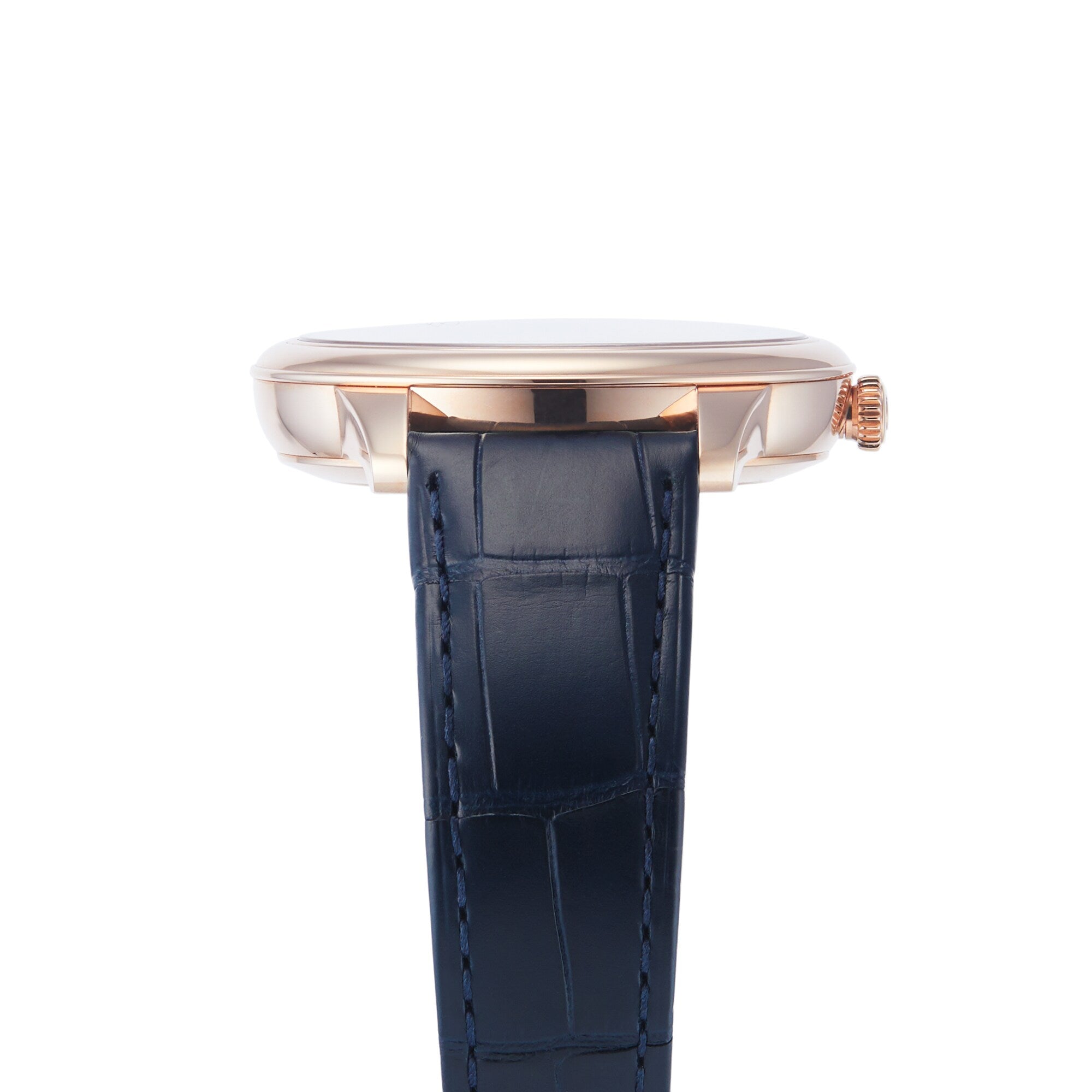 Side view of the OMEGA De Ville Prestige wristwatch with a rose gold case and dark blue leather strap against a white background.