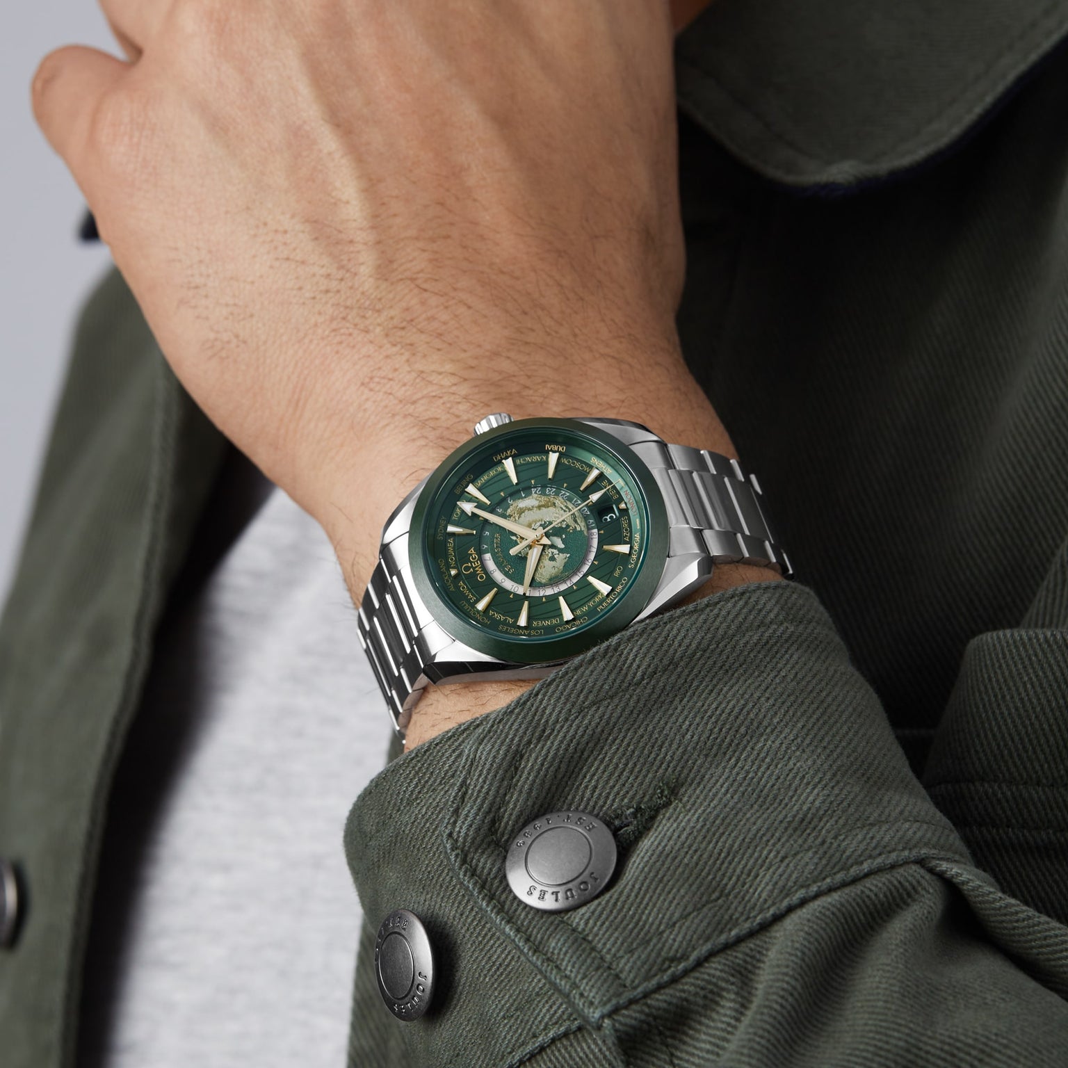A person wearing an OMEGA Seamaster Aqua Terra 150M with a stainless steel case and green dial, paired with a matching green jacket.