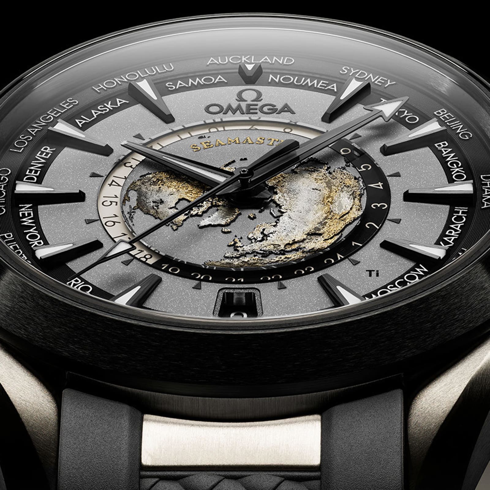 A close-up of the OMEGA Seamaster Aqua Terra 150M watch face showcases a detailed world map, city names around the dial, black and gold accents, and a sleek titanium case.