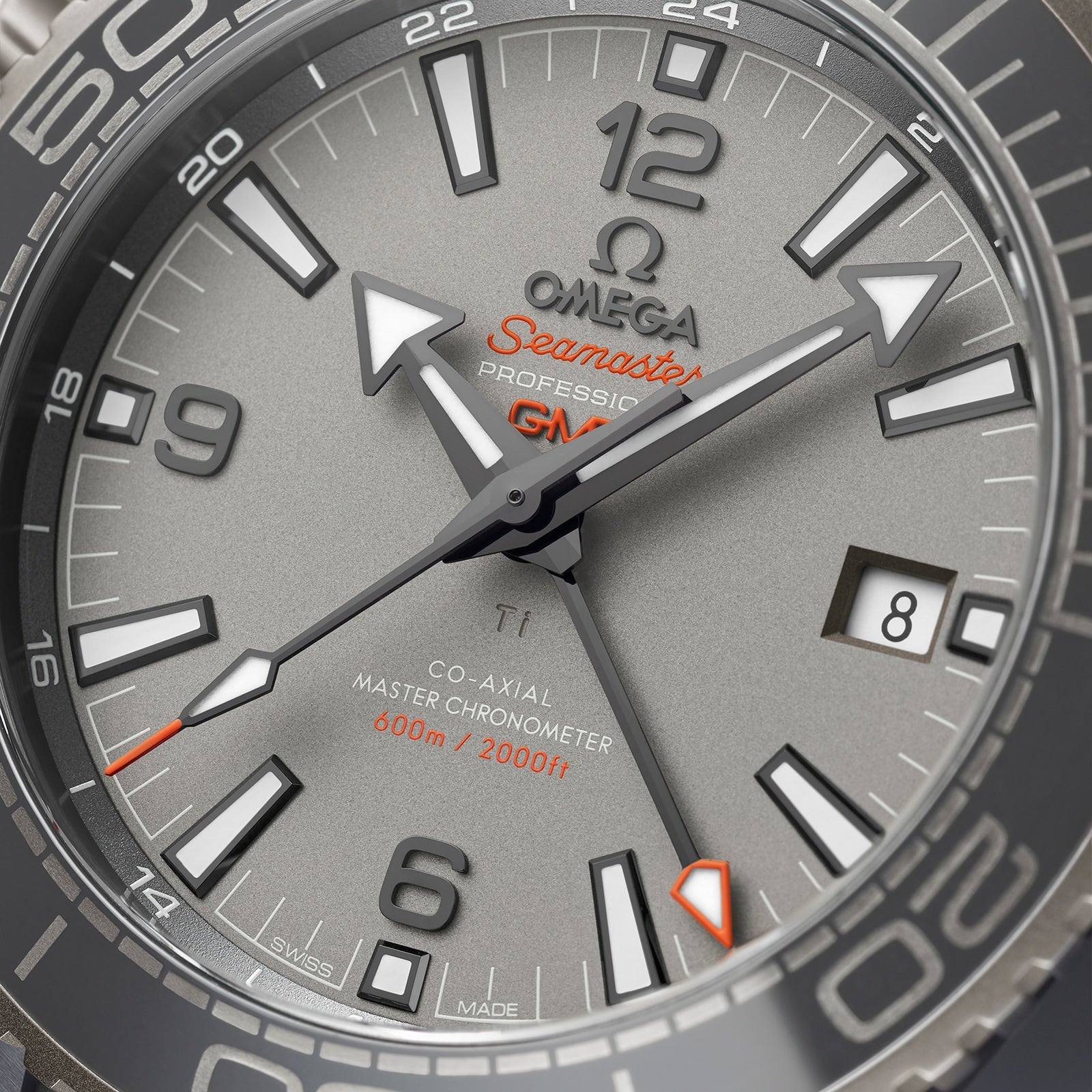 Close-up of an OMEGA Seamaster Planet Ocean 600M watch face at 10:08 with the date set to the 8th, displaying a gray dial, bold markers, orange accents, and certified Master Chronometer precision.