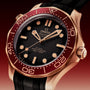A close-up of the OMEGA Seamaster Diver 300M featuring a red bezel, Bronze Gold case, black dial and strap, showing the time at 10:09.