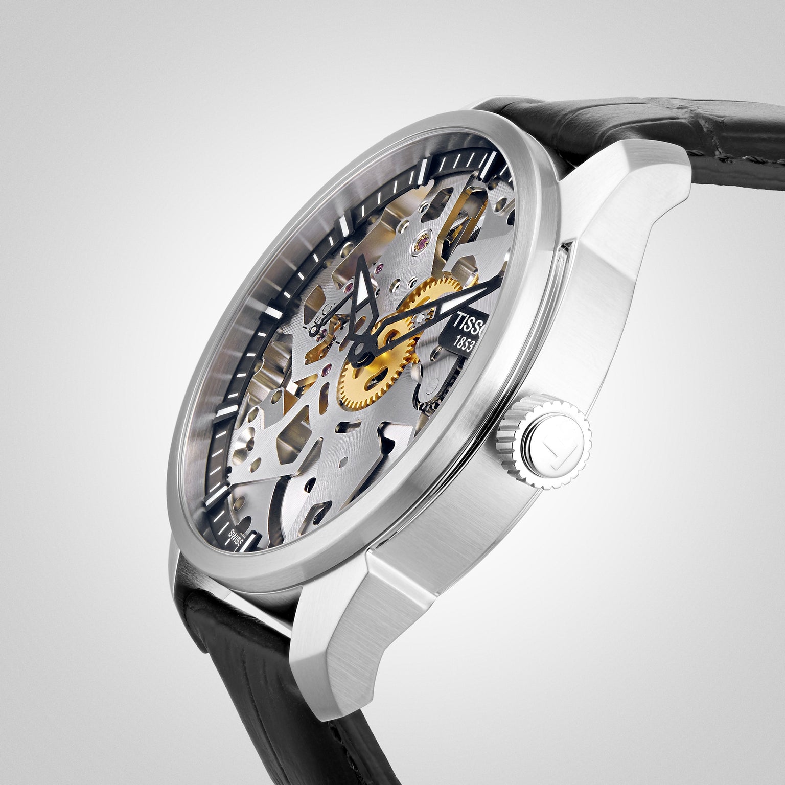 Tissot T-Complication Squelette Mechanical watch featuring visible gears, a black leather strap, and a textured crown displayed on a white background.
