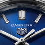 Close-up of the TAG Heuer Carrera Date watch face, showcasing its blue sunray dial, silver hour markers, and sleek hands partially displaying the time.