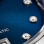 Close-up of the TAG Heuer Carrera Date watch, showcasing a blue sunray dial with diamond hour markers and a partial view of the silver AUTOMATIC inscription.