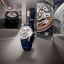 The Vacheron Constantin Traditionnelle Complete Calendar Openface, a luxury platinum skeleton watch with a blue leather strap, is displayed upright amid reflective panels revealing its detailed engravings, openwork movement, and calendar complications.