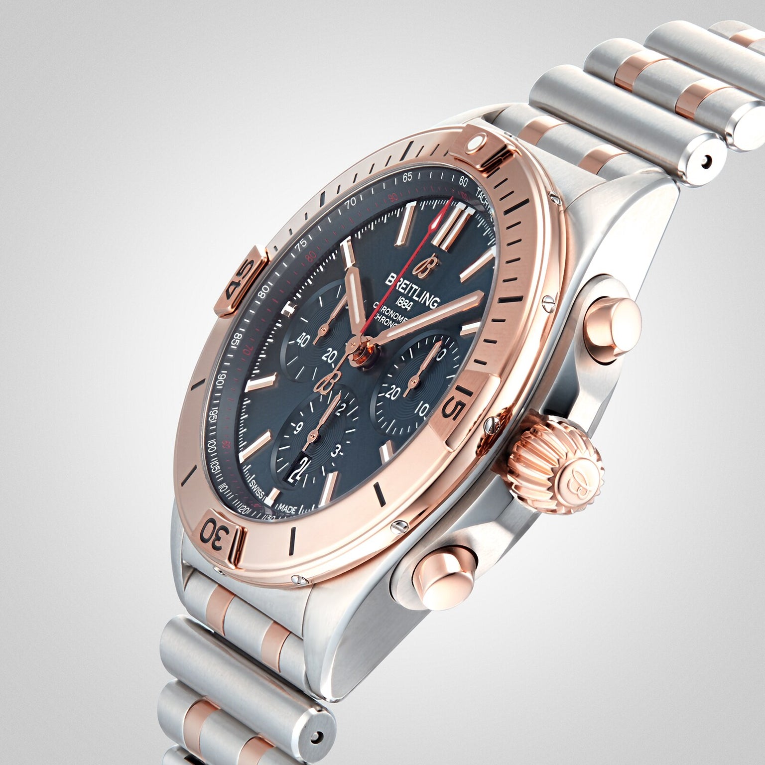 The Breitling Chronomat B01 42 features a silver and rose gold bracelet, black dial with three subdials, and rose gold bezel, crown, and pushers, highlighting the acclaimed Breitling 01 movement in an angled photo.