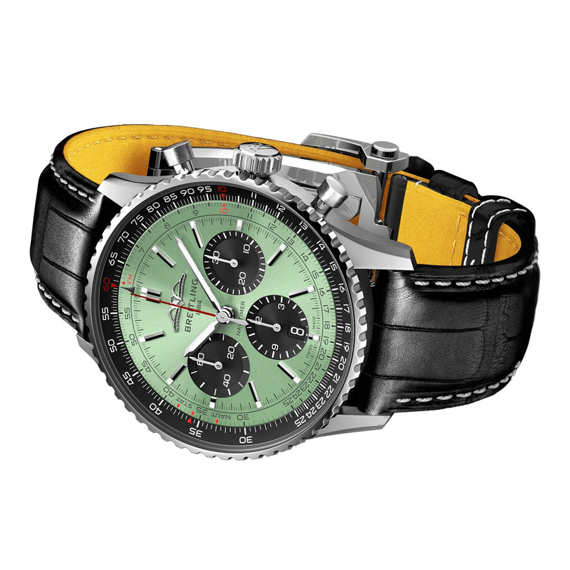 The Breitling Navitimer B01 Chronograph 43 features a green dial with three black subdials, a black bezel, and a black leather strap with white stitching and yellow lining, powered by the Breitling 01 calibre.