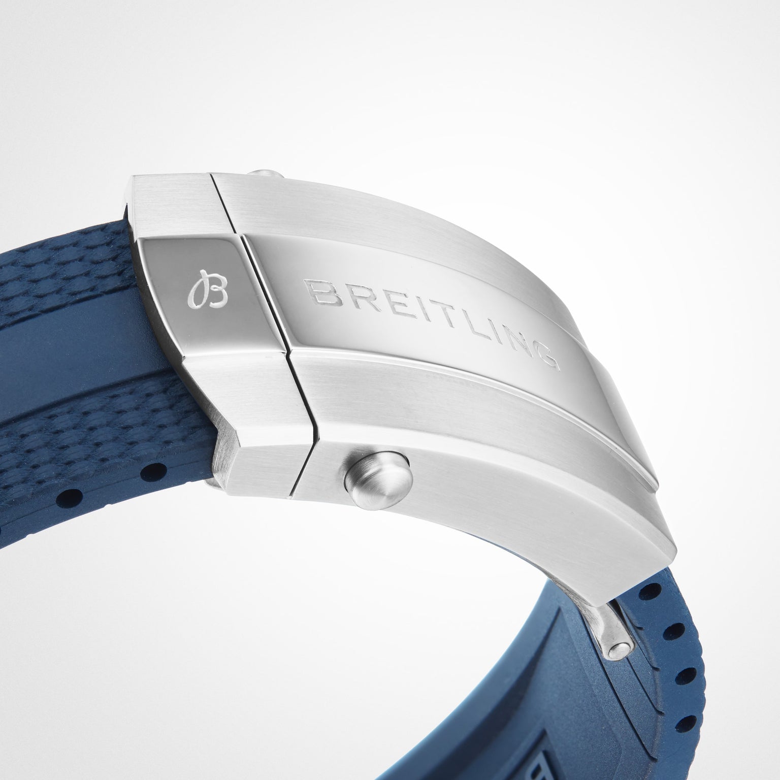 Close-up of a stainless steel Breitling clasp with engraved branding on a textured blue rubber strap, featured on the Superocean Automatic 42 dive watch.