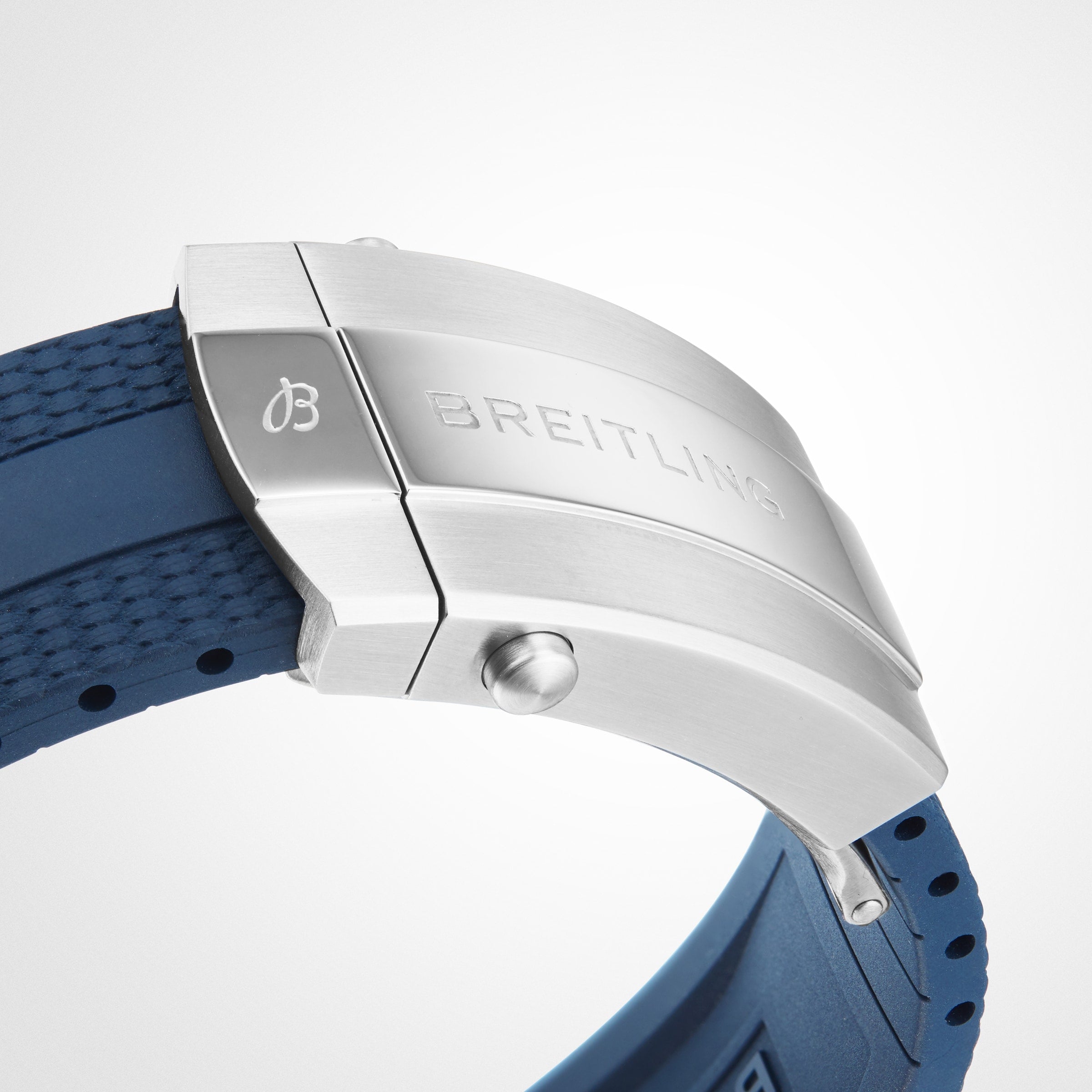 Close-up of a stainless steel Breitling clasp with engraved branding on a textured blue rubber strap, featured on the Superocean Automatic 42 dive watch.
