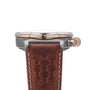 Side view of the Breitling Chronomat B01 42 Triumph wristwatch featuring a brown leather strap and rose gold accents on the bezel and crown.