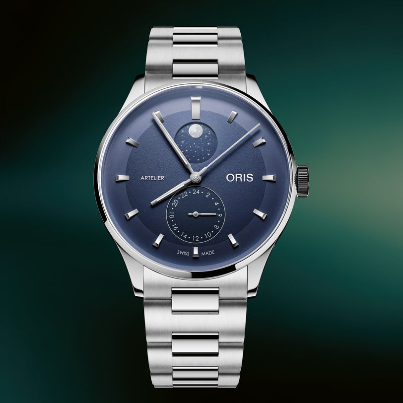 Silver stainless steel watch with dark blue dial, moonphase complication at top, subsidiary dial at bottom, and matching meta