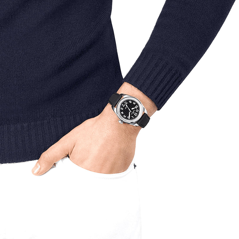 A person in a navy sweater and white pants has their left hand in their pocket, showcasing the Zenith Pilot Automatic watch.