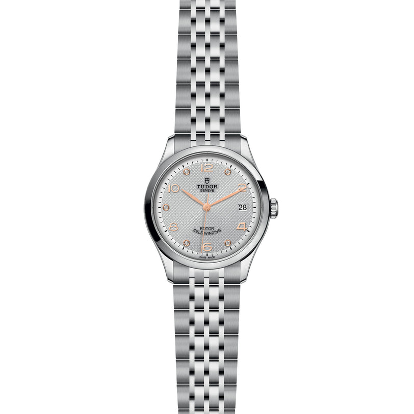 The TUDOR 1926 is a silver wristwatch with a stainless steel bracelet, white dial, gold markers, date at 3 o’clock, and three hands—ideal for lovers of timeless TUDOR style and classic mechanical watches.
