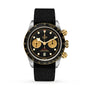 The TUDOR Black Bay Chrono S&G features a black dial, gold subdials and pushers, plus a black fabric strap—combining sporty chronograph style with signature diver watch heritage, shown here against a white background.