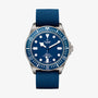 The TUDOR Pelagos FXD is a blue dive watch with a round face, titanium case, rotating bezel, fabric strap, and 200m water resistance, displaying the time 10:11.