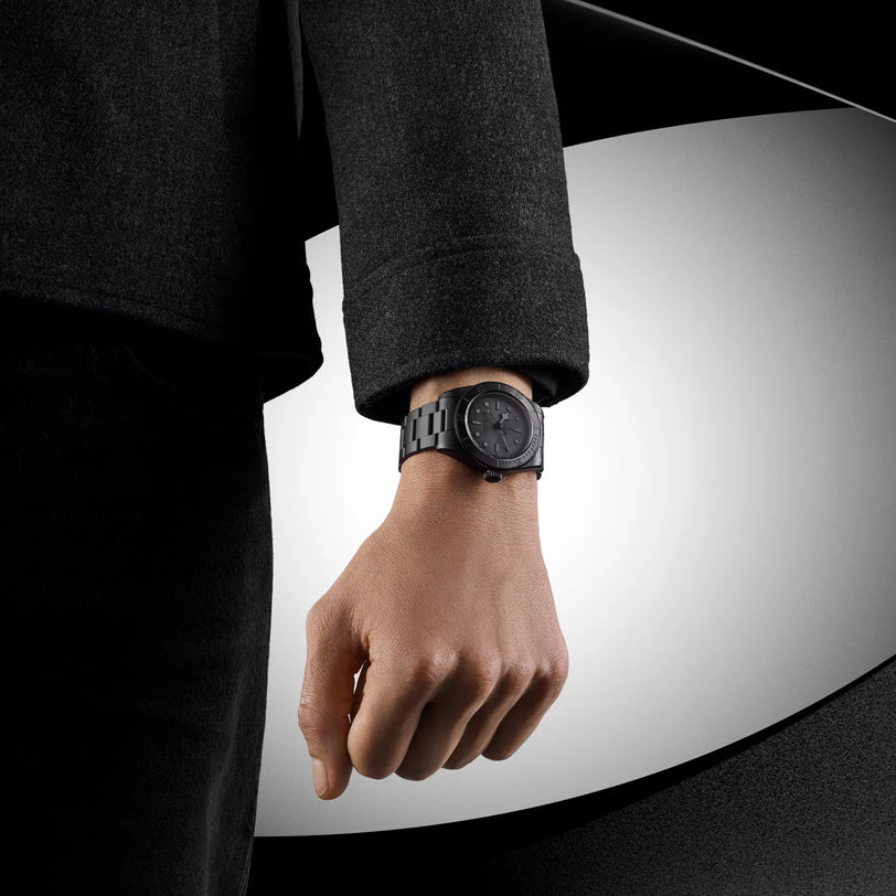 Black watch with ceramic bezel worn on wrist with dark suit jacket.