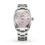 The Grand Seiko Spring Drive Heritage is a silver wristwatch with a textured light pink dial, date display, and metal bracelet.