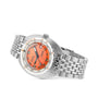 The DOXA Sub 300 Professional is a stainless steel diver’s watch with an orange dial, black hour markers, unidirectional bezel, date window, and metal link bracelet, displayed at an angle on a white background.