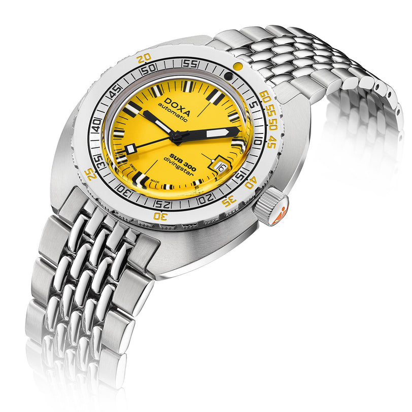 The DOXA Sub 300 Divingstar is a stainless steel diver’s watch with a yellow dial, unidirectional bezel, black and orange hands, date at 3 o’clock, and a linked metal bracelet.