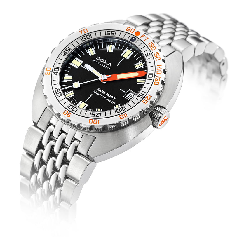 The DOXA Sub 300T Sharkhunter is a stainless steel diver’s watch with a black dial, orange minute hand, Super-LumiNova markers, date display, and comes on a metal bracelet.