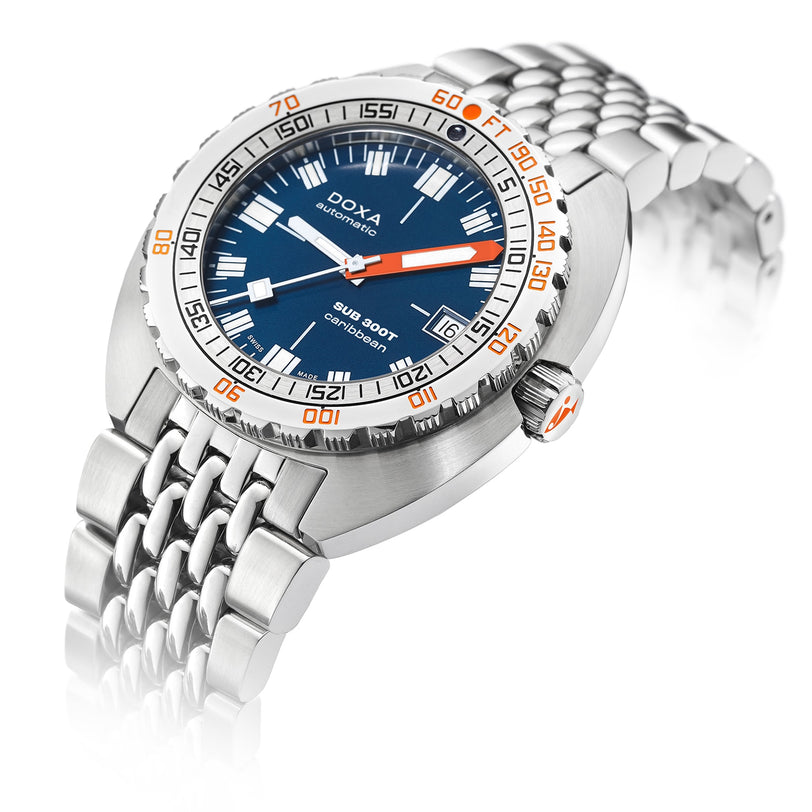 A DOXA Sub 300T Caribbean diver’s watch in stainless steel, featuring a blue dial, orange minute hand, rotating bezel, and metal bracelet is shown at an angle.