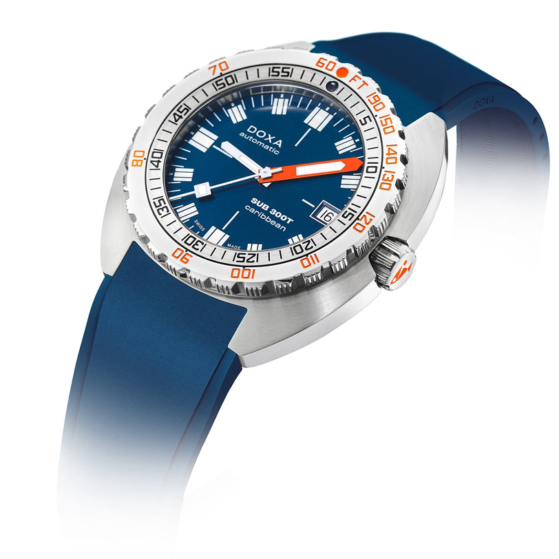 The DOXA Sub 300T Caribbean is an automatic divers watch with a blue dial, orange accents, blue rubber strap, rotating bezel, bold hour markers, and a helium release valve for deep-sea performance.
