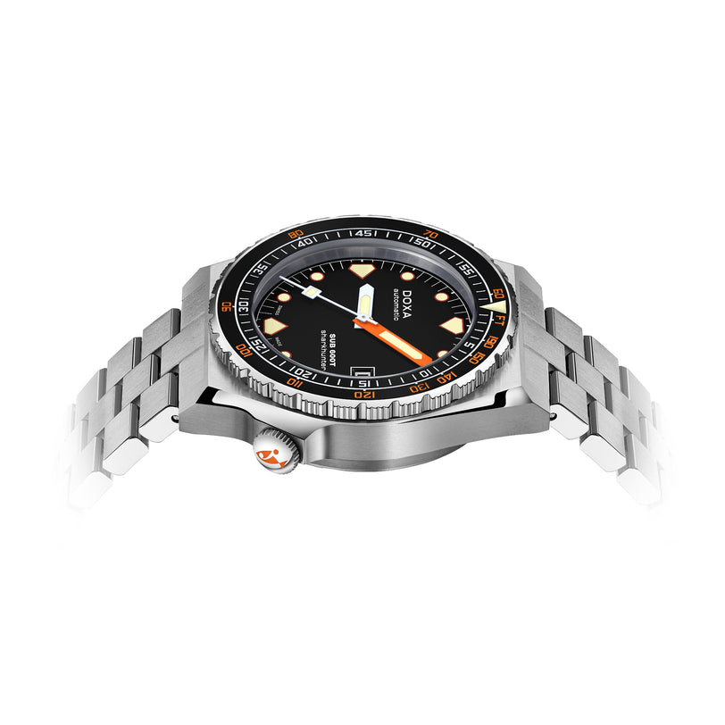 The DOXA Sub 600T Sharkhunter, a stainless steel dive watch with a black dial, orange and white accents, and a metal bracelet, is displayed from a side angle on a white background.