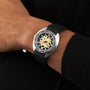 A person wearing a black long-sleeve shirt and a DOXA Army Stainless Steel watch by DOXA, featuring a cream dial with bold black and orange accents plus Super-LumiNova® coating for enhanced readability.