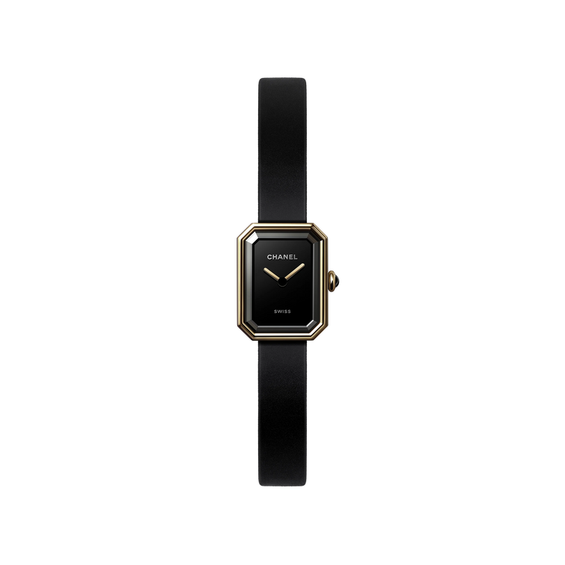 The Chanel Première Ribbon is a minimalist wristwatch with a slim black leather strap and a small octagonal black-lacquered dial edged in yellow gold, featuring gold hands, the Chanel logo, and "SWISS" in white.