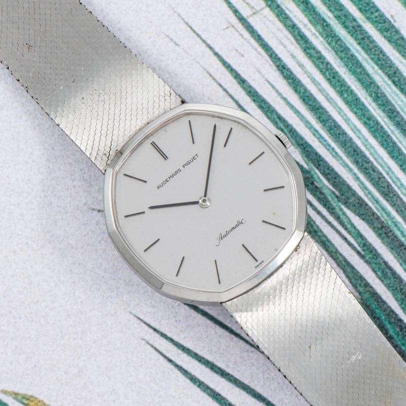 An Audemars Piguet Steel Dress Watch with a mesh band is displayed on a white and green patterned surface.