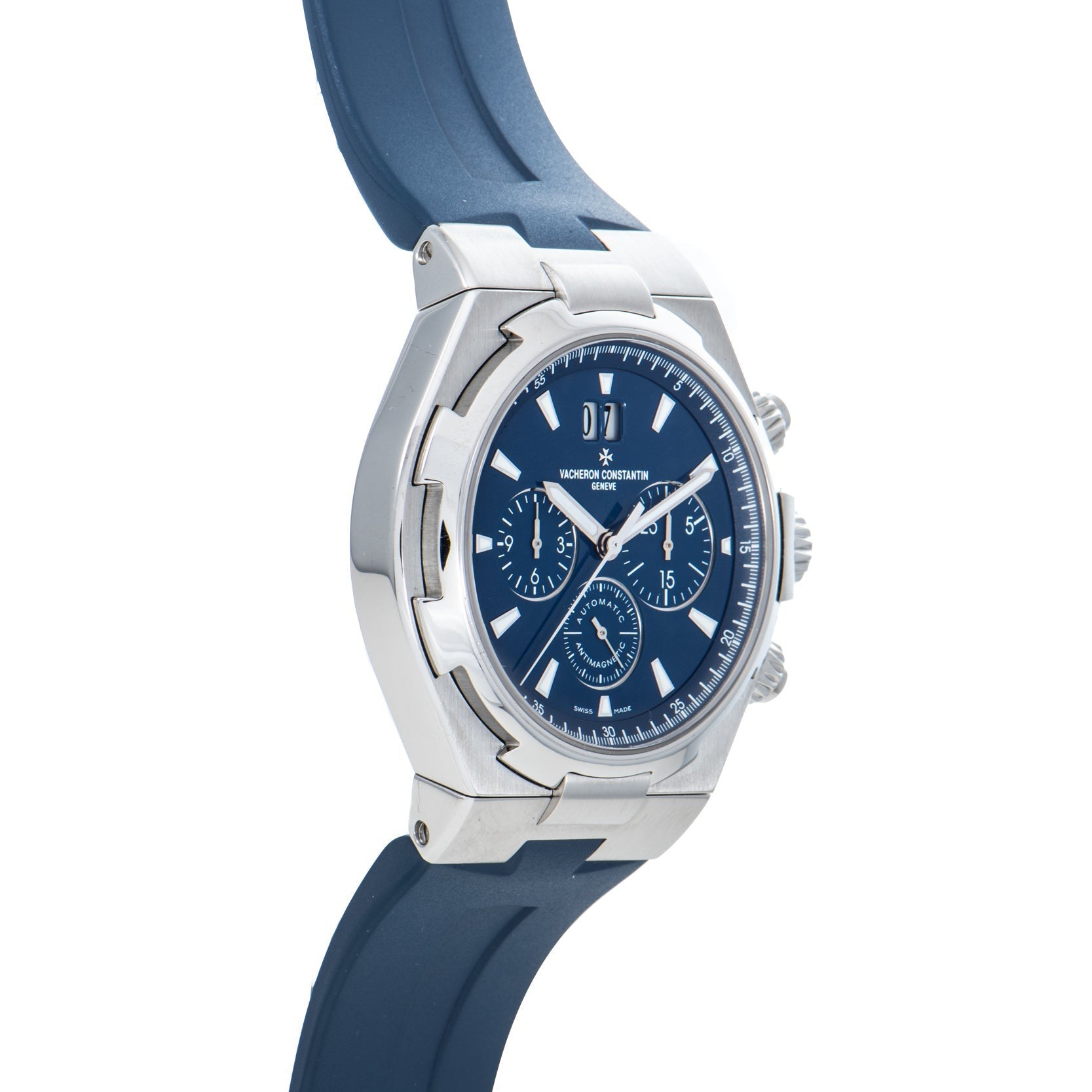 The Vacheron Constantin Overseas Chronograph features a silver case, blue dial with three subdials, and a blue rubber strap, displayed at an angle.