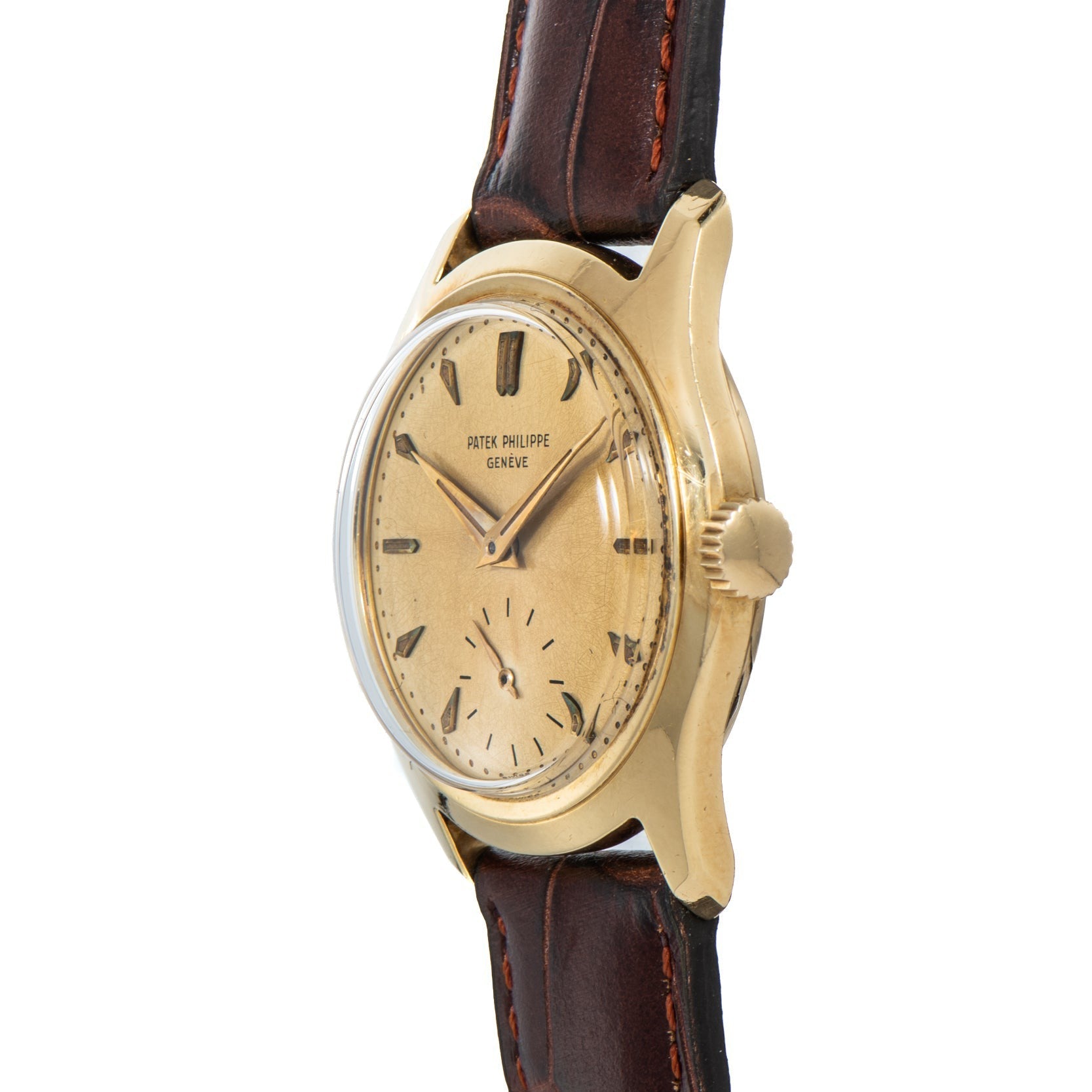 Patek Philippe Calatrava gold wristwatch with a worn dial and brown leather strap, viewed from an angle.