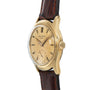 Patek Philippe Calatrava gold wristwatch with a worn dial and brown leather strap, viewed from an angle.