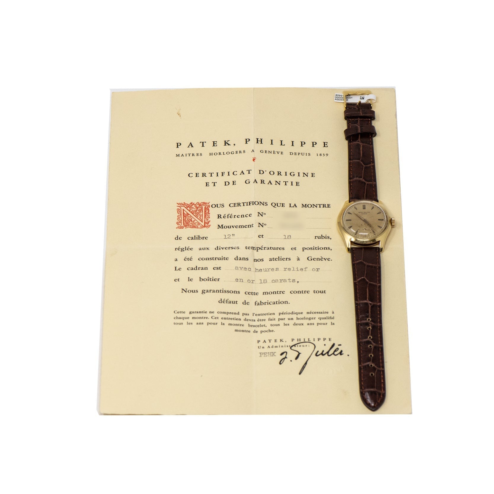 A Patek Philippe Calatrava gold wristwatch with a brown leather strap placed on its certificate.