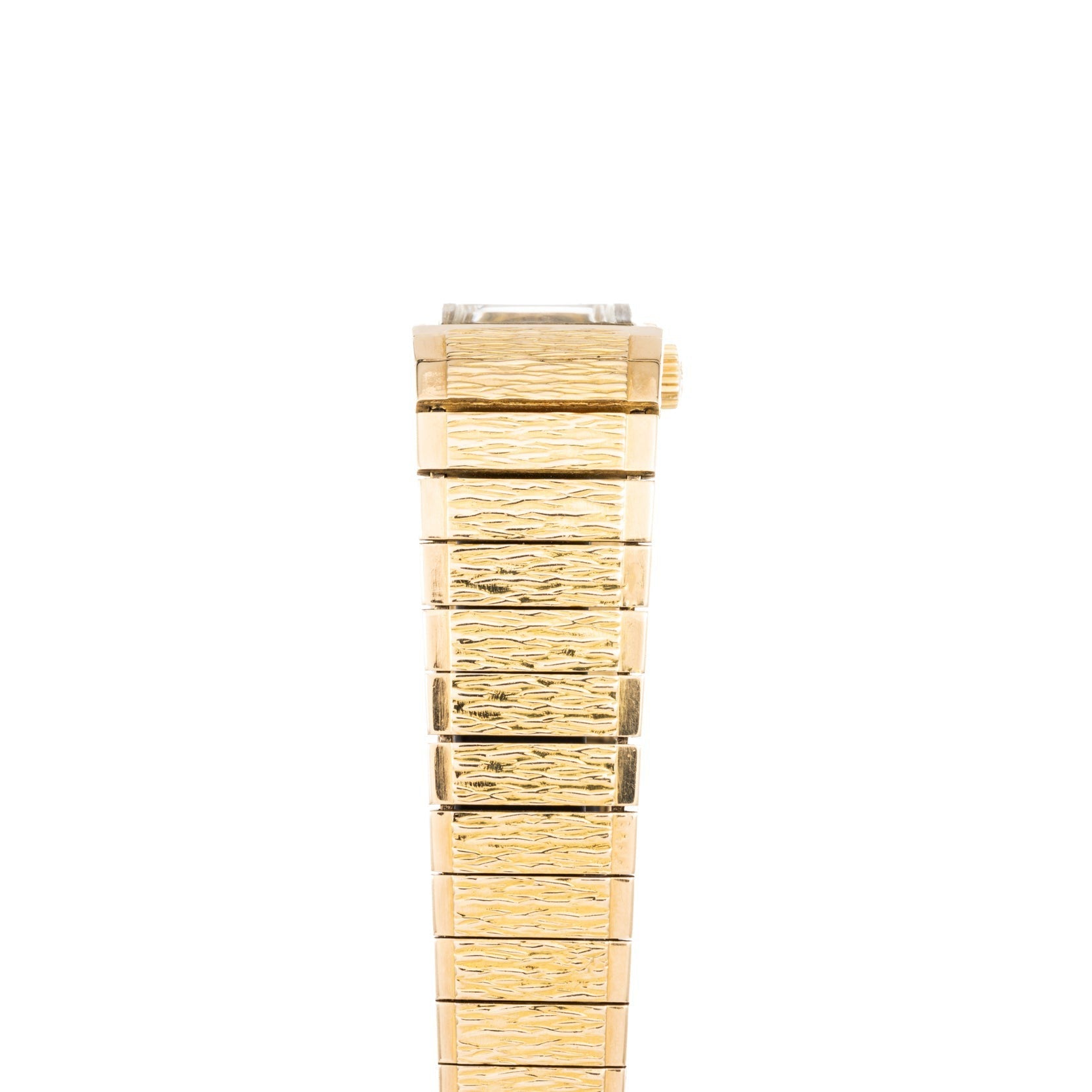 A Patek Philippe Yellow Gold Integrated Dress Watch is displayed vertically from the side, emphasizing its textured metal band.