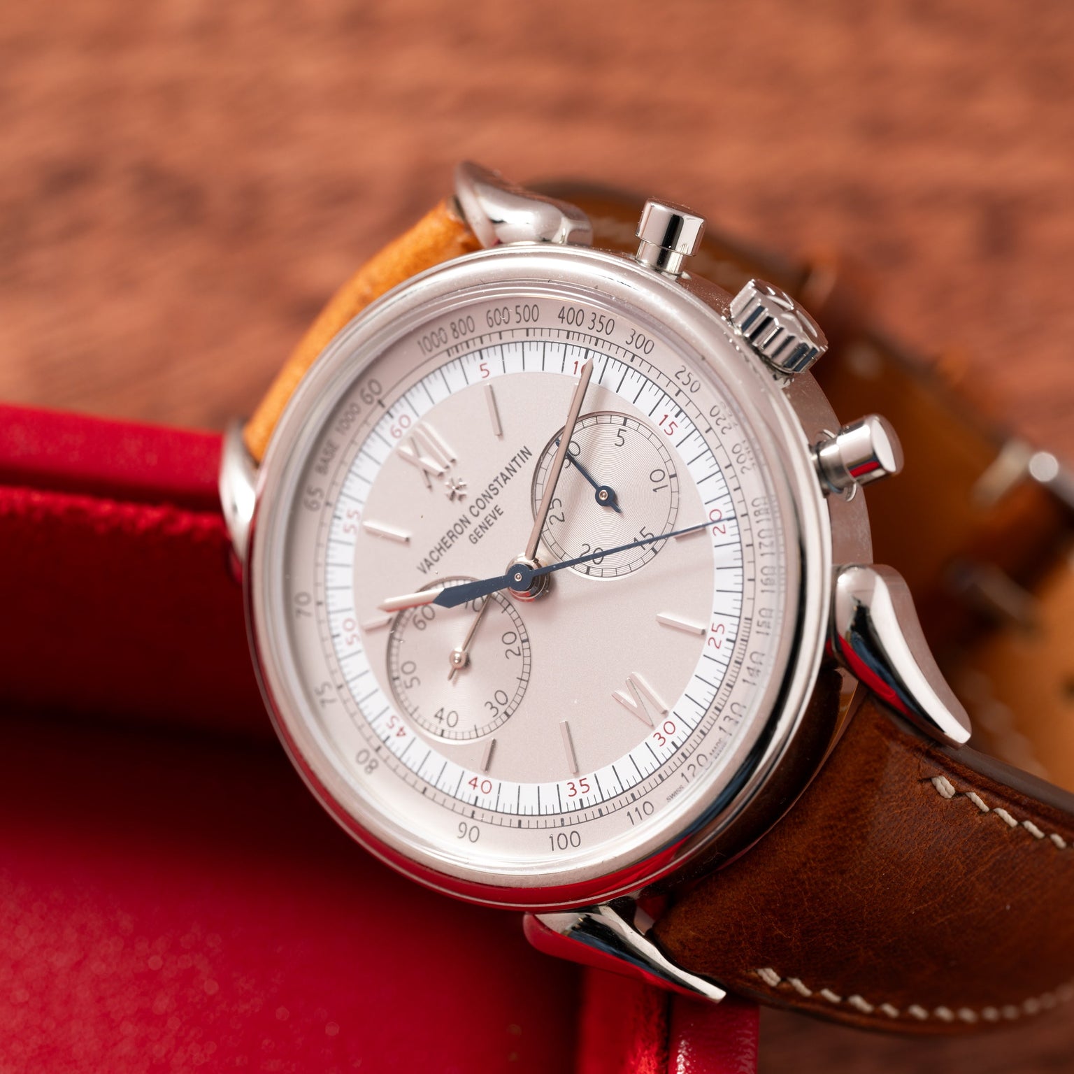 The Vacheron Constantin Historiques Cornes De Vache Chronograph, a luxury watch with a brown leather strap, displayed on a wooden surface.