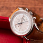 The Vacheron Constantin Historiques Cornes De Vache Chronograph, a luxury watch with a brown leather strap, displayed on a wooden surface.