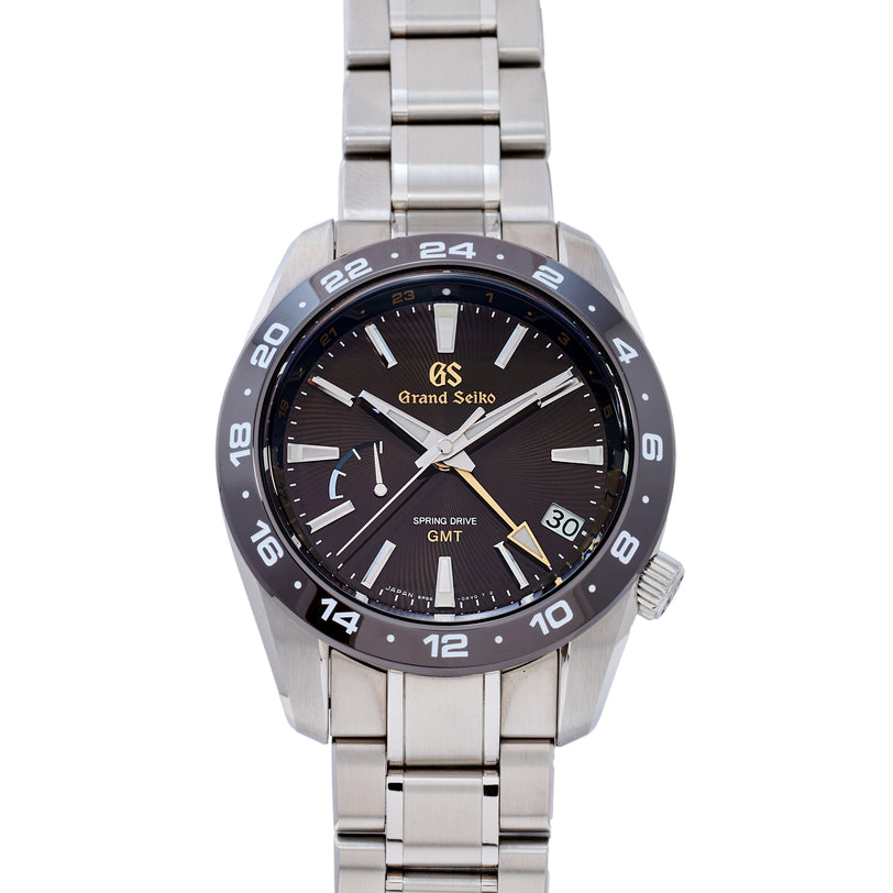 Grand Seiko watch with black dial and silver metal strap on a white background