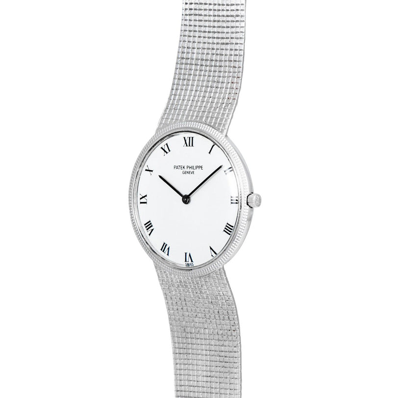 The Patek Philippe Calatrava features a silver case, white dial with Roman numerals, and a textured metal bracelet.