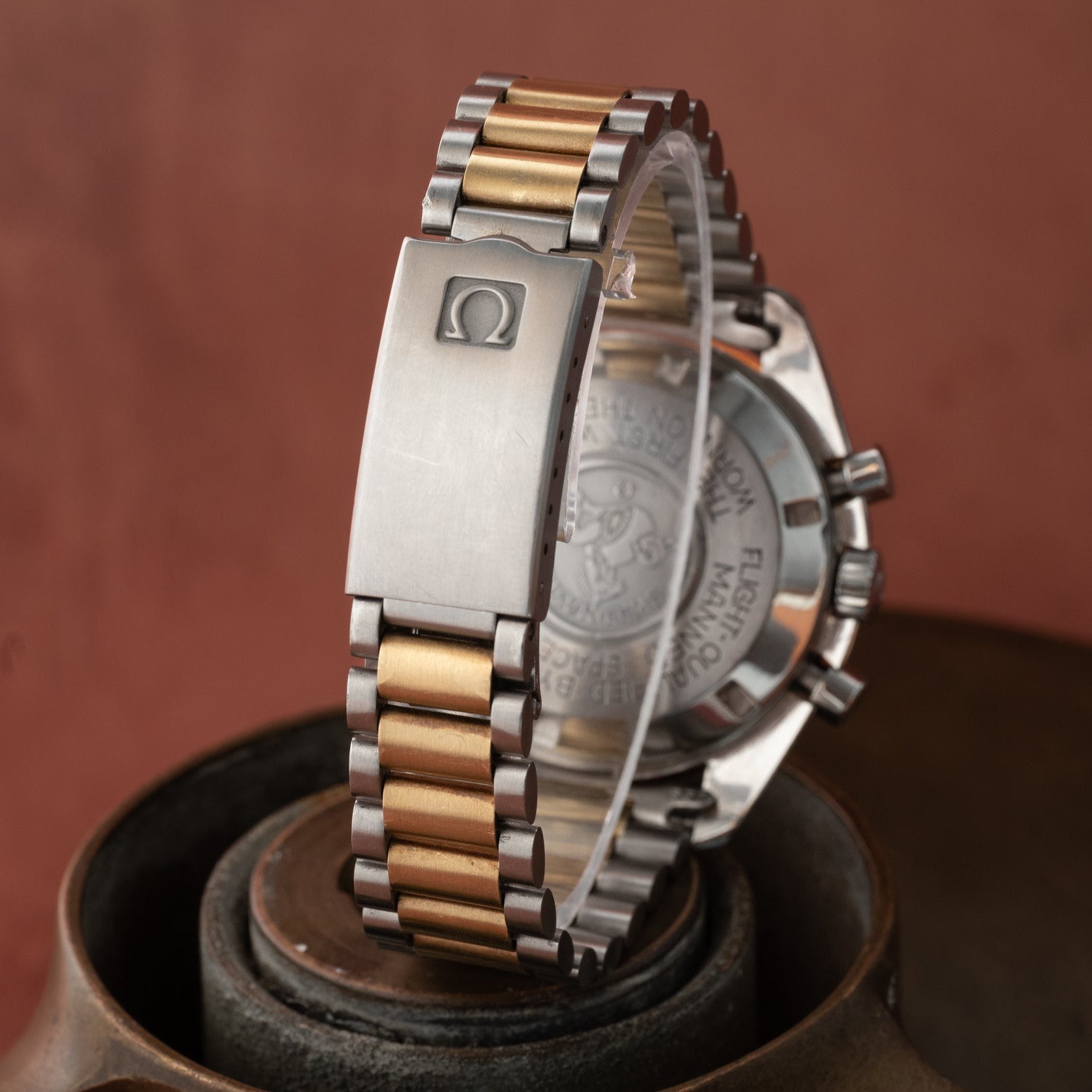 A close-up of the OMEGA Speedmaster Professional Two-Tone, featuring its silver and gold metal bracelet, with a clear view of the clasp and case back.