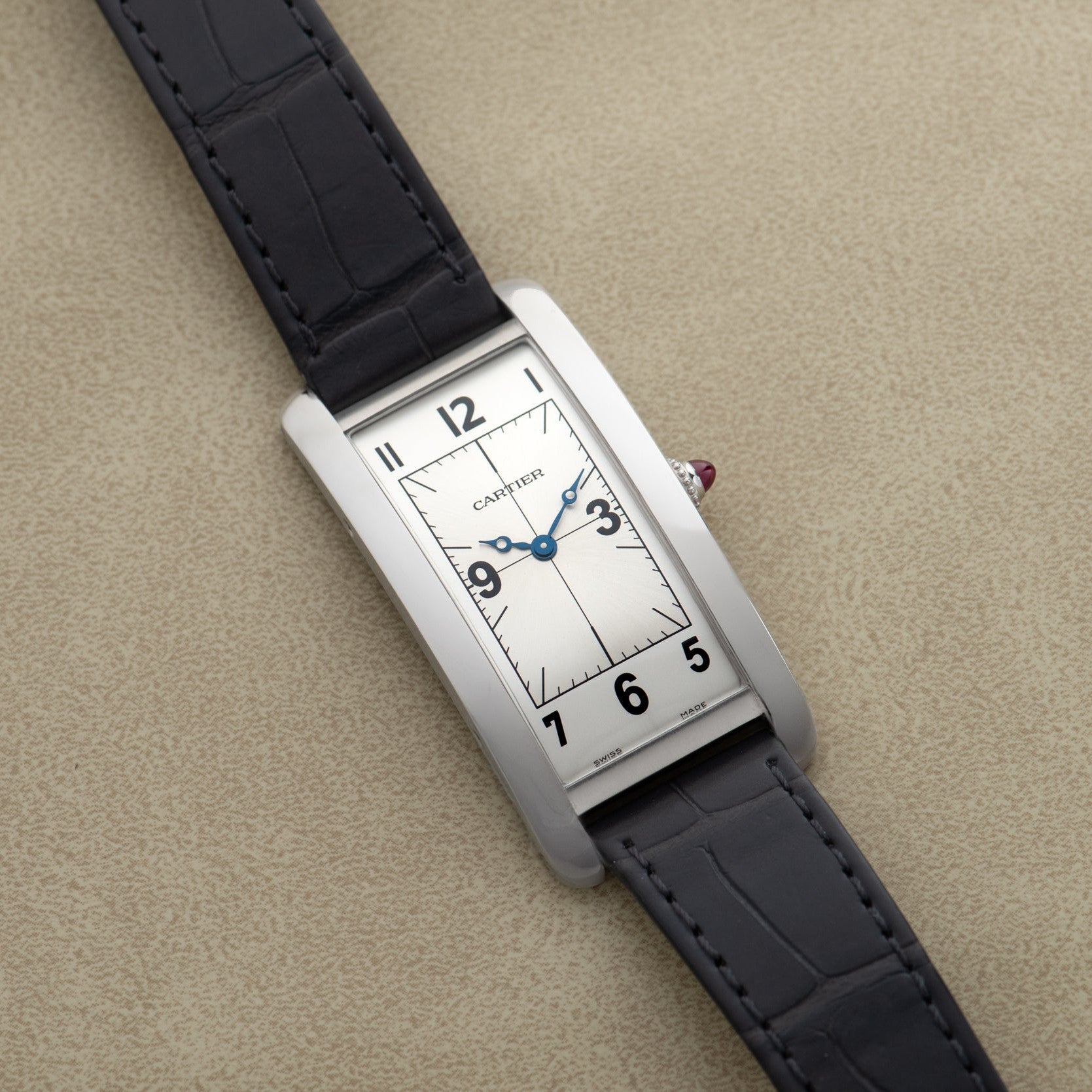 The Cartier Tank Cintrée Piece Unique is a rectangular wristwatch featuring a silver dial, black numerals, and a black leather strap.