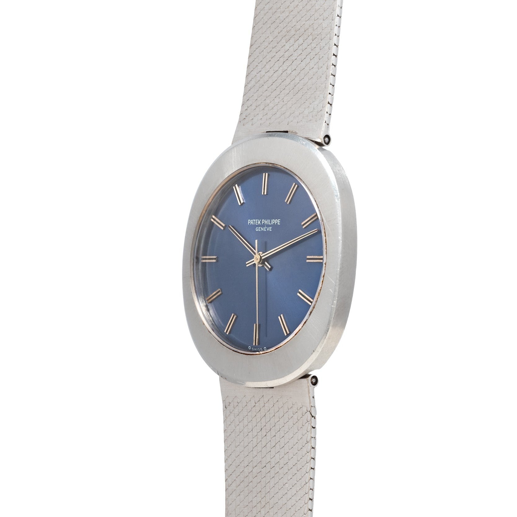 The Patek Philippe Dress Watch UFO features a silver case, blue dial, gold hour markers, and a textured silver band, displayed at an angle.