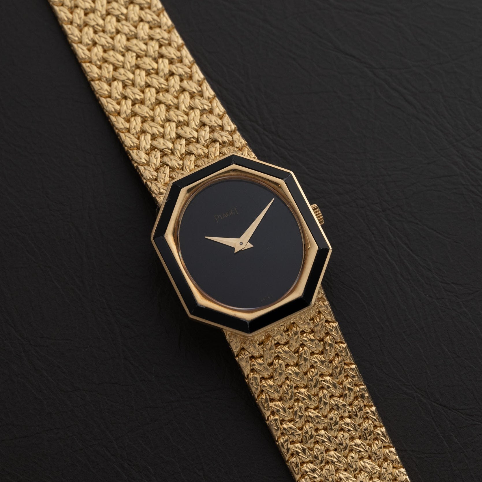 The Piaget Onyx Dial wristwatch features a black octagonal face without hour markers, set on a textured gold band and pictured against black leather.